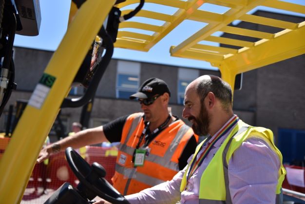 Close up picture of a candidate driving a fork lift truck under supervision from the instructor