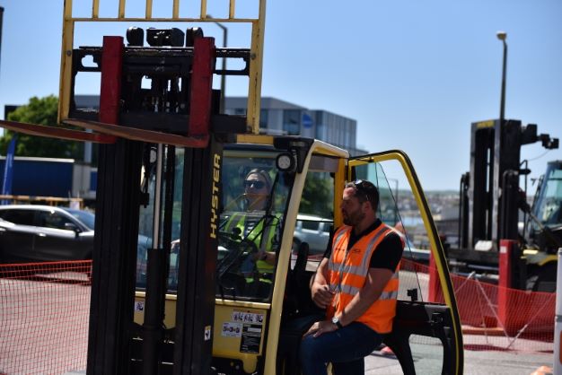 Forklift truck instructor guiding a pupil through the use of hydraulic controls
