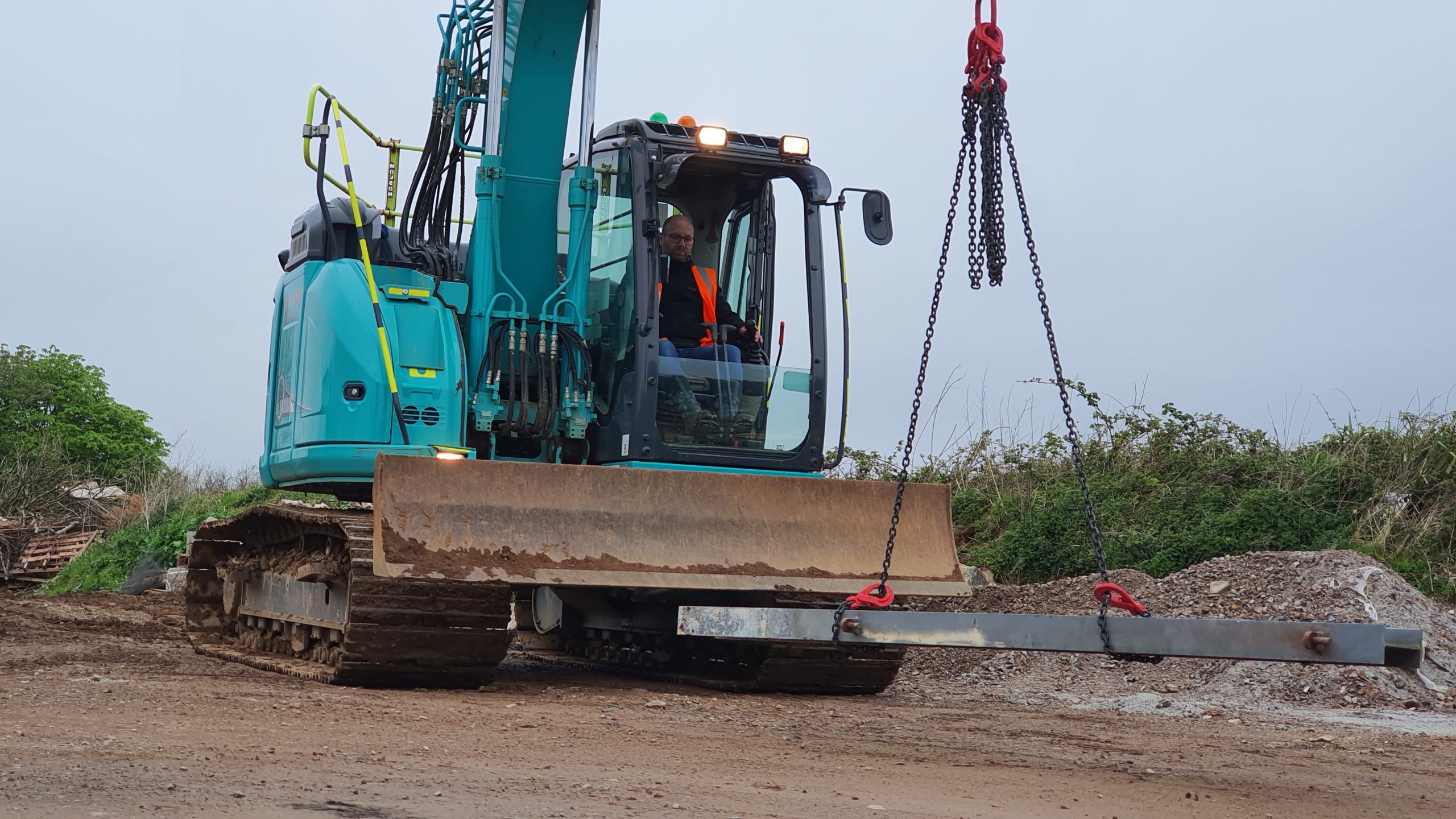excavator carrying a suspended steel profile using chain slings