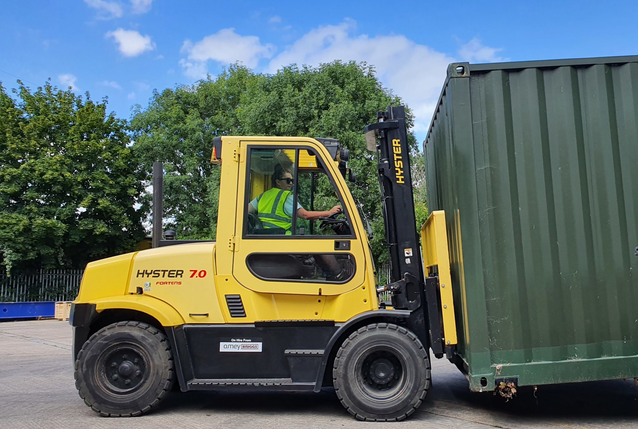 Counterbalance lift truck carrying a green shipping container