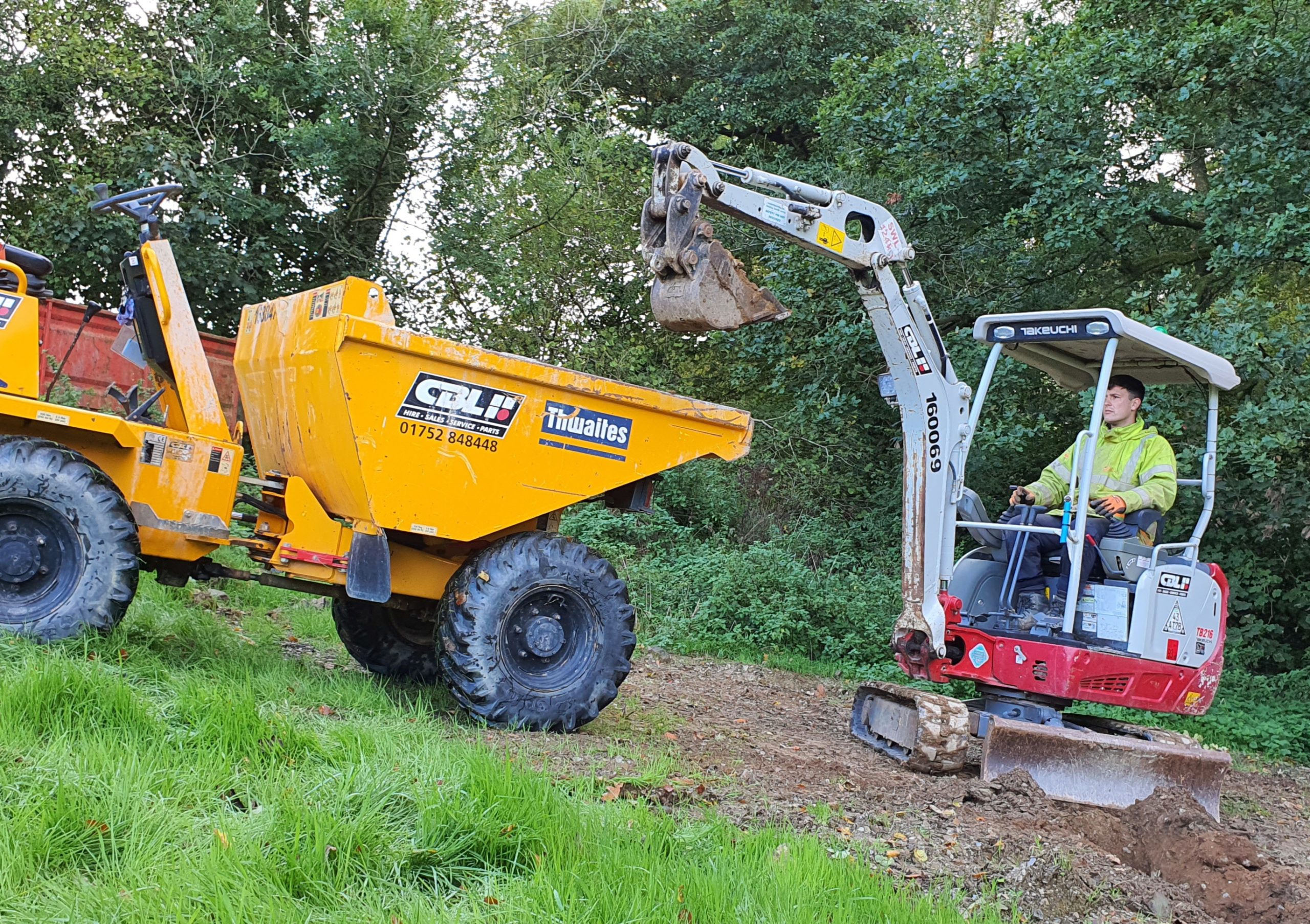 small excavator loading a 3t dumper in a field with trees in background
